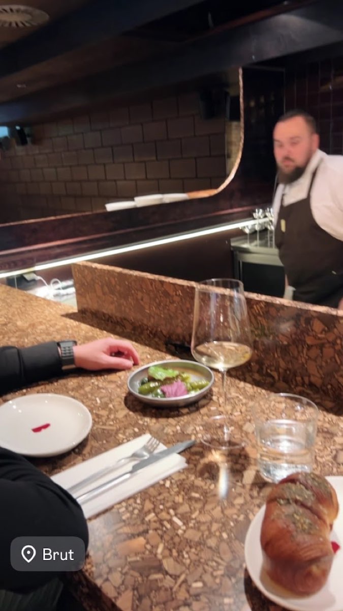 Bar w BRUT, kieliszek białego wina naturalnego i mały talerz przy korkowej ladzie